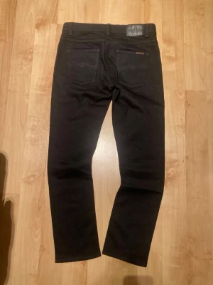 Nudie Jeans: Dude Dan:32/32 - Säljer Nudie Jeans pågrund av att de inte kommer till användning, Jeansen är nästan helt oanvänd då jag bara har använt de ett fåtal gånger. Jeansen är raka/ smala. Jag rekommenderar jeansen starkt om du gillar en clean/ stilren look😃  Märke: Nudie Model: Dude Dan Material: Bomull 99% Elastan 1% Storlek: 32/32 🎨:Svart 📏:Finns att skicka 🚚: Skickas inom 1-2 dagar  OBS!! Fråga efter mått innan du köper!  Priset kan diskuteras😁