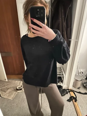 Svart basic tröja med rund hals - En svart, enkel tröja med rund hals och långa ärmar. Perfekt för en avslappnad stil och lätt att matcha med andra plagg. Tröjan har en rak passform och ser mjuk ut i materialet.