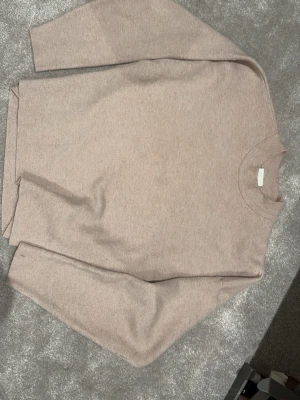 Beige basic tröja med rund hals - Super mjuk beige stickad tröja med rund halsringning och långa ärmar. Perfekt för lager-på-lager och enkel att matcha med olika outfits. Den har inye blivit nopprig förutom lite som alla stickade tröjor har🥰 Den har ett pytte litet hår vid armen, skriv om fler bilder!