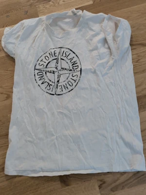 Vit  t-shirt - Vit t-shirt med klassisk logga tryckt på bröstet. T-shirten har rund hals och korta ärmar, perfekt för en avslappnad stil. Tillverkad i mjuk bomull som känns skön mot huden. L men passar även XL!