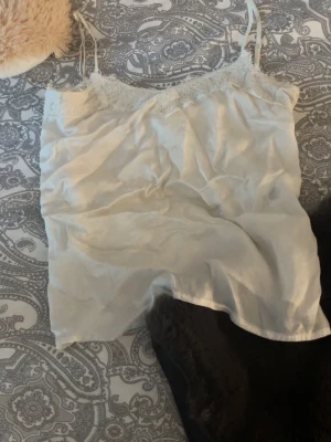 Vit spetslinnetopp med tunna band - Säljer en söt vit linne med spets, de är jätte skönt material och luftigt. Perfekt till sommaren!!