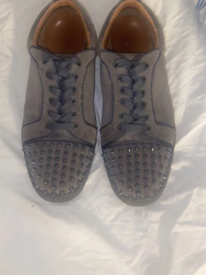 Grey louboutin shoes w spikes - Snygga skor till vardagen, fest och egentligen allt. Kommer med louboutin sko påse och Louboutin sko box. Har haft dom en stund men nästan inte använt dom. Några av spikarna har tappat lite färg men enkelt att fixa. Annars är dom i god tillstånd. Bara att ge pris förslag