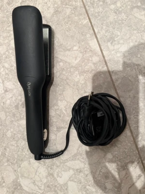 Svart plattång från GHD Max - Säljer en svart plattång från GHD Max med breda keramiska plattor och sladd. Perfekt för att snabbt styla och räta ut håret. Ergonomisk design och enkel att använda. Passar både långt och tjockt hår.