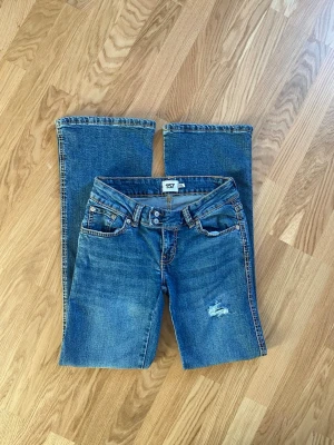 Blå bootcut jeans Paris Stitch - Blåa lågmidjade jeans från lager 157 i modellen Paris stitch. Storlek S med full längd, passar hyfsat bra i längden på mig som är 172 cm. Jag har gjort egna hål i jeansen som jag tycker har hållit bra. Nypris för jeansen är 400kr.