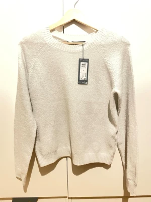 Abow white stickad tröja från vero Moda  - Ljus stickad tröja från vero Moda helt ny med prislapp påmed rund halsringning och långa ärmar. Tröjan har en enkel och stilren design med ribbade muddar vid ärmslut och nederkant. Perfekt för lager-på-lager och passar till många olika outfits.