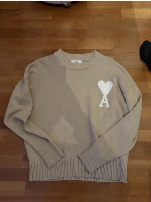 Ami Paris tröja  - Snygg Ami Paris tröja i färgen beige. Tröjan är i storlek M. Köpte tröjan för 1200 på plick gilla den jättemycket men tycker den sitter lite stort på mig så vill sälja. Den är i jättebra skick och material.