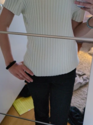 Vit ribbad kortärmad topp - Snygg vit ribbad topp med korta ärmar och rund hals. Toppen har en klassisk passform och är tillverkad i ett mjukt material som känns skönt mot huden. Perfekt att matcha med jeans eller kjol för en clean look.