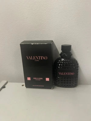Valentino Uomo Born In Roma Intense - Valentino Uomo Born In Roma Intense är en lyxig parfym med en elegant svart flaska i mönstrat glas och rosa detaljer. Flaskan har en unik, nitar-inspirerad design och svart kork. Doften är Eau de Parfum Intense och kommer i originalförpackning. Priset går och förhandla är lite använd mer svar privat
