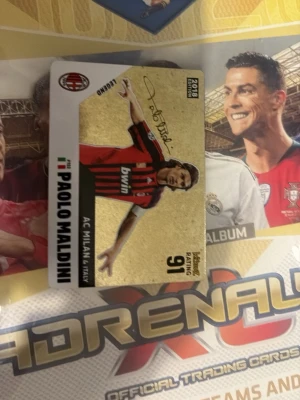 Ett jätte rare Paolo Maldini samlarkort Adrenalyn XL från 2018 - Samlarkort med Paolo Maldini från Adrenalyn XL-serien 2008/2009. Kortet har guldfärgad bakgrund, AC Milan-logga och spelarens namn samt statistik. Perfekt för fotbollsfans och samlare av sportkort.