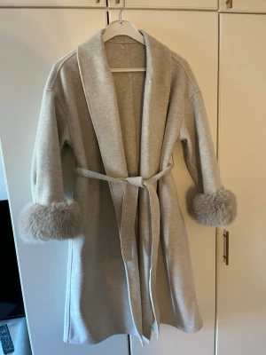 Elegant kappa med päls armar - En elegant och fin kappa med päls på ärmarna helt ny användt endast en gång one size passar alla mellan storlek S-L  har inga tecken på användning ser helt ny ut