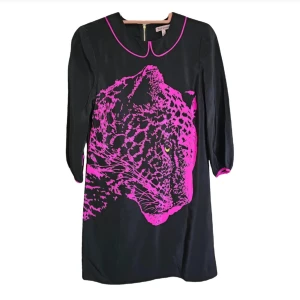 Svart klänning med leopardmönster från Juicy Couture - Snygg svart klänning från Juicy Couture med ett iögonfallande rosa leopardmönster framtill. Klänningen har trekvartsärmar och en dragkedja i ryggen. Perfekt för en djärv stil! 100 % silk 