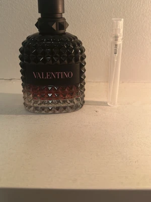 Valentino parfym born in Roma intense - Snygg parfym från Valentino i en cool, svart och transparent glasflaska med nitar och mönstrad yta. Flaskan har en mörk överdel och rödaktig botten. Perfekt för dig som gillar lyxiga och trendiga dofter.