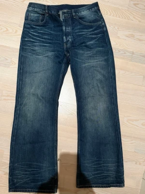 Acne studios jeans 2021m  - Säljer ett par blå jeans från Acne Studios med klassisk femficksdesign och breda ben. Jeansen har en mörk tvätt med snygga slitningar och detaljerad söm. Materialet är 100% bomull och de har en läderpatch med Acne Studios-logga bak i midjan.