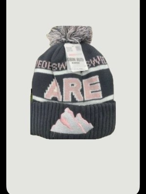 Åre mössa - Bilden visar en stickad mössa från Robin Ruth med texten 'ÅRE' och ett bergmotiv, men ingen väst finns med på bilden. Skriv vid minsta fundering. Pris ej hugget Sten 🪨