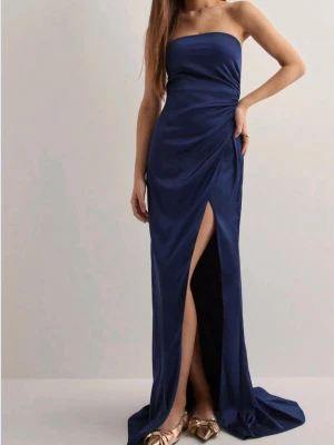 Marinblå axelbandslös långklänning - Säljer en marinblå axelbandslös långklänning, från Nelly. Helt ny med prislapp kvar! 