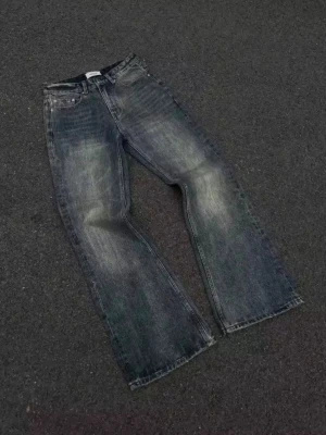 HERR Mörkblå bootcut jeans  - Snygga bootcut jeans i en mörkblå tvätt med slitningar och klassisk femficksdesign. Jeansen har normal passform och är tillverkade i robust denim som ger en cool vintagekänsla. Perfekta för dig som gillar avslappnad stil med lite edge.