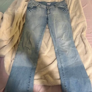 Ljusblå lågmidjade jeans med broderade kronor - Victoria Beckham liknande jeans!😍ljusblå lågmidjade jeans från Madonna med snyggt slitna detaljer och broderade kronor på bakfickorna. Jeansen har klassisk femficksmodell, raka ben och låg midja. Perfekta för dig som gillar en avslappnad och cool stil. Size M!!
