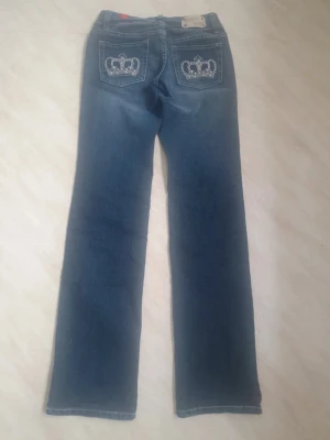 Blå Jeans med kronbroderi på fickorna Str S - Snygga blå jeans från 5PM med raka ben och normal passform. Baktill finns broderade kronor med pärlor och strassdetaljer på fickorna som ger extra bling. Super snygga 💕