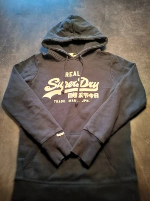 Superdry Hoddie  - Fin superdry Hoddie i väldigt bra skick. Storlek S. 62cm lång rekommenderas till smalare personer för den har lite tajt passform 