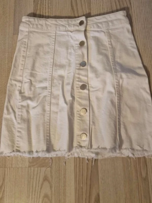 Vit kortkjol med knappar - Säljer en vit jeanskjol. Jätte fin och perfekt till dig som vill fixa en fin outfit för sommaren. Kjolen är köpt från new worker för några år sedan så tror ej att den finns kvar och köpa.