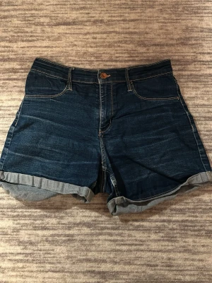 Mörkblå denimshorts &Denim - Säljer ett par mörkblå jeansshorts från &Denim. Inga riktiga fickor fram