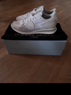 Philippe Model sneakers - Snygga vita sneakers från Philippe Model med rund tå och platt sula. Skorna har snörning och är tillverkade i en mix av skinn och textil, med detaljer i mocka på sidorna och framtill. Stilren design med diskret logga på sidan och tungan. Jättefint skick, sparsamt använda🤗Allt på bilden medföljer vid köp