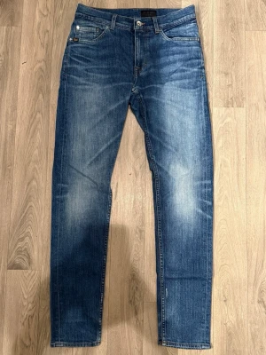 Tiger of Sweden Evolve Jeans Blå W30 L32 - Blåa Tiger of Sweden Evolve jeans i fint skick (Snygga slitningar) i storlek W30/L32. Mått - Midja: 36,5cm, Benlängd: 102cm. Modellen är 185cm & 63kg. Hör av dig vid funderingar!🤩