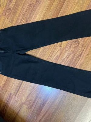 Svarta low straight jeans från Monki - Svarta jeans från Monki med rak passform och låg midja. Klassisk femficksdesign, silverfärgade nitar och dragkedja i gylfen. Materialet är slitstark bomull med en mjuk jeanskänsla. Perfekt för dig som gillar enkel och clean stil.