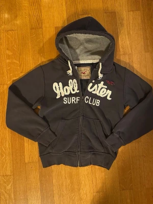 Hollister surf club vintage hoodie - Riktigt snygg hoodie från hollister med en vintage känsla! Storlek xs(står S på lappen) och passar folk under 170cm. Är 176cm på bilden. Riktigt go passform!😁 Bra skick, utan defekter. Tveka inte på att skicka prisförslag och frågor!✌️