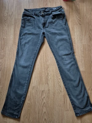 Replay jeans Katewin grå, storlek 30 - Snygga grå jeans från Replay i modellen Katewin, storlek 30. Klassisk femficksdesign med raka ben och normal passform. Jeansen har Replay-logga på bakfickan och är tillverkade i mjukt bomullsmaterial med lite stretch för extra komfort.
