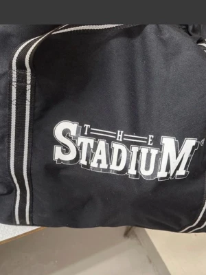 Svart träningsväska Stadium - Svart väska från Stadium. Perfekt för träning eller resa.  Knapparna på väskan har trillat nedantill, väskan håller nog ett tag till   Höjd: cirka 58 cm, bredd: cirka 35 cm, längd cirka 70 cm