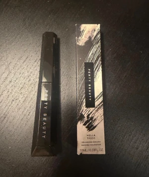 Fenty Beauty Hella Thicc Mascara Oanvänd - Volymgivande mascara från Fenty Beauty i färgen svart. Kommer i en snygg, kantig svart tub med tillhörande förpackning. Heter Hella Thicc och innehåller 10 ml. Perfekt för att få fylliga och dramatiska fransar.
