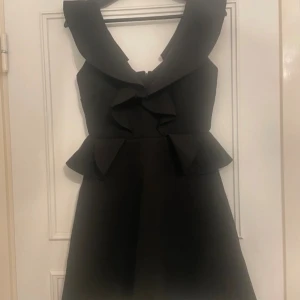 Svart River Island klänning med volanger - Svart River Island klänning med volanger, storlek UK 8 / EUR 34 (funkar till XS-S). Bilderna gör den inte riktigt rättvis, den är helt svart i verkligheten. Ny/oanvänd.