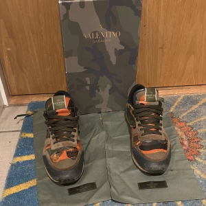 Valentino Garavani Rockrunner sneakers - Säljer ett par Valentino Garavani Rockrunner sneakers med camouflagemönster i grönt, orange och beige. Skorna har snörning, platt sula och detaljer i mocka, skinn och textil. Ikonisk design med coola färgblock och klassisk logga på plösen. Kommer med originalkartong och dustbags.