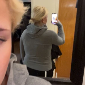 Grå hoodie med dragkedja - Säljer en grå hoodie med dragkedja framtill och huva. Tröjan har långa ärmar, ribbade muddar och två fickor framtill. Perfekt för chill dagar eller när du vill vara bekväm. Klassisk och enkel stil som funkar till det mesta.