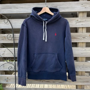 Ralph Lauren Hoodie - Mörkblå Ralph Lauren Hoodie i storlek S, passar XS/S. Den har inga hål eller fläckar, men den är lite urtvättad o solblekt i färgenPå ryggen har den blivit lite solblekt, på bild 3 kan man se hur färgen är påväg att släppa. Jag rekommenderar köpare att använda mörkblå textilspray för att färga om,  eller färgmedel i tvätt. Borde gå att göra fin igen mer rätt utrustning! 