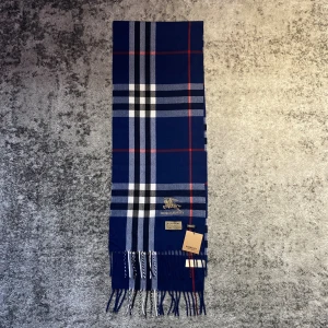 Marinblå burberry halsduk - Skön halsduk i nytt skick, passar perfekt till kyligare dagar då den värmer och är elegant samtidigt. Orginalkartong mm medföljer.