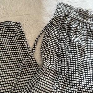 Svartvita Zara byxor med snörning - •Snygga byxor med svartvitt rutigt mönster och elastisk midja med snörning.  •Använda 1 gång och tvättade. Som nya •Lätta och luftiga, perfekta för en chill stil.  •Byxorna har en relaxed passform och är tillverkade i ett mjukt tyg som känns skönt mot huden. •Djurfritt och rökfritt hem