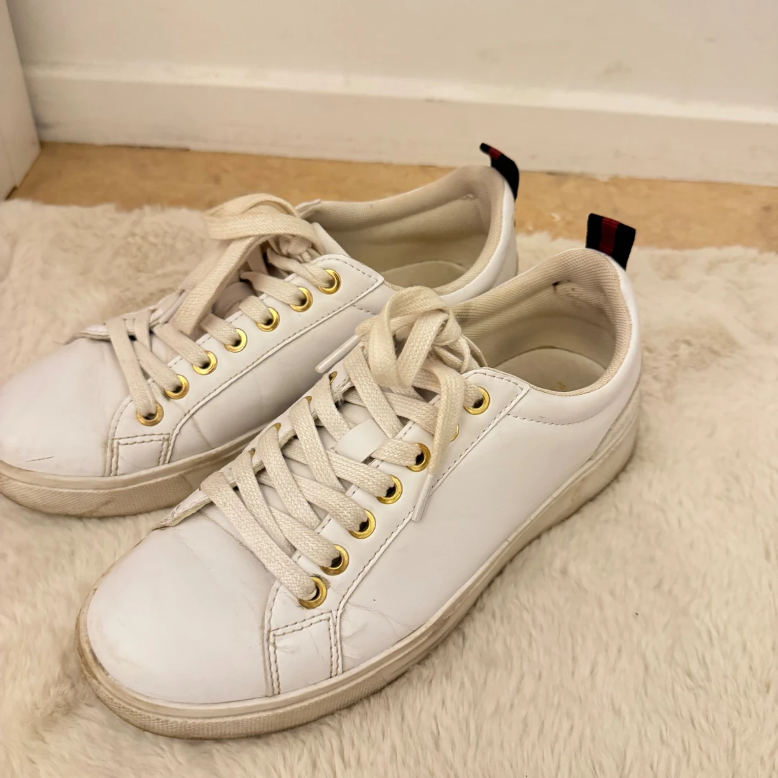 Vita sneakers med gulddetaljer