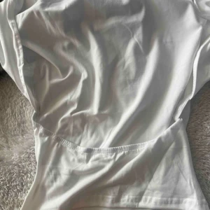 Vit croppad topp med tight passform - Säljer en stilren vit croppad topp med korta ärmar och tight passform. Toppen är tillverkad i ett mjukt och stretchigt material som sitter snyggt mot kroppen. Perfekt till jeans eller kjol för en fräsch look.