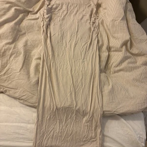 Beige långkjol från Gina Tricot - Säljer en beige långkjol från Gina Tricot i mjukt och stretchigt material. Kjolen har rynkade detaljer längs sidorna som ger en snygg siluett. Perfekt för dig som gillar en enkel men trendig look.