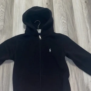 Svart hoodie från Polo Ralph Lauren - Svart hoodie från Polo Ralph Lauren med vit broderad logga på bröstet. Tröjan passar i S och M inte L 