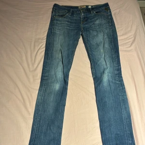 Blå Rockxanne jeans W29 Replay - Snygga blå jeans från Rockxanne i klassisk femficksmodell med raka ben och diskret slitning framtill. Jeansen har gul kontrastsöm och detaljerade bakfickor. Perfekt passform för dig som gillar en tidlös look.