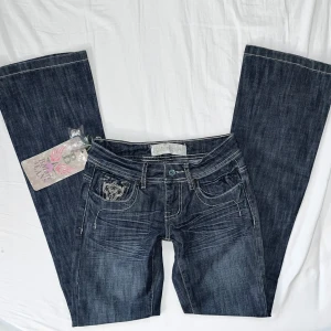 Vintage bootcut lågmidjade jeans - Snygga mörkblå jeans med bootcut passform och coola broderade detaljer bak och framtill. Helt nya med lappar kvar. Strl XS 💗 // midja 33cm tvärsöver, innerbenslängd 80cm