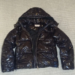 Svart glansig pufferjacka från Nelly - Säljer en svart, glansig pufferjacka från Nelly i storlek XXS. Jätte fin vinterjacka perfekt för dig som gillar stockholmsstil🩷 jackan har ett pyttelitet hål i fickan men det är inget som märks av🩷