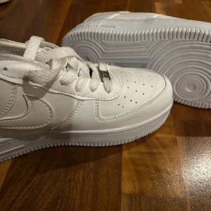 Sneakers  - Säljer ett par fejk, vita Nike Air Force sneakers. De har en stilren design med snörning och perforerade detaljer på ovansidan för extra ventilation. Perfekta för en casual look.💖