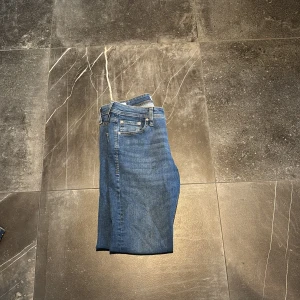 Slim Glenn blå jeans storlek 30/32 - Snygga blå jeans från Slim Glenn i storlek 30/32. Modellen har klassisk femficksdesign, slim passform och raka ben. Jeansen är tillverkade i mjukt denimtyg med orangea sömmar och har en normal midja. Perfekta för dig som gillar stilrena och bekväma jeans. Pris kan diskuteras 