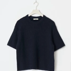 Mörkblå stickad kortärmad tröja - Säljer en stilren mörkblå stickad tröja från Filippa K. Tröjan har korta ärmar, rund halsringning och en boxig, lite loose passform. Perfekt att styla med jeans eller kjol för en clean look.