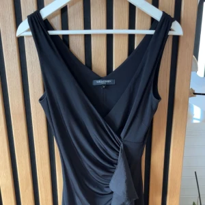 Omlottklänning - Supersnygg svart omlottklänning från Ilse Jacobsen med v-ringning och volangdetaljer framtill.  I jättefint skick
