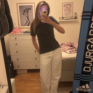 Mörkgrå t-shirt med hög krage Soyaconcept - Mörkgrå t-shirt från Soyaconcept med högre ribbad krage och korta ärmar. Modellen är rak och har en clean look utan tryck eller mönster. Skön och mjuk känsla, perfekt till jeans eller vida byxor.